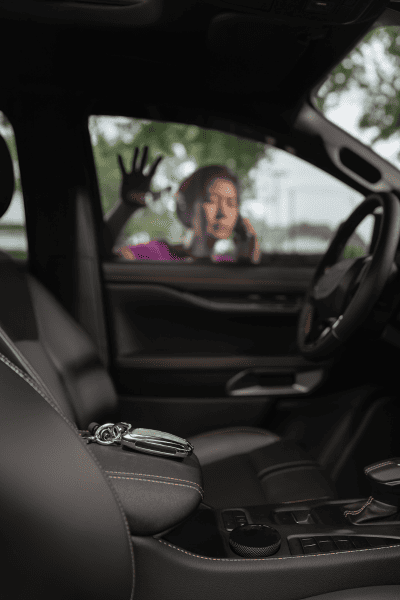 A woman stands outside a car with her hands on the window, looking in at a set of keys left on the front seat—time to call Locksmith Redlands for help.