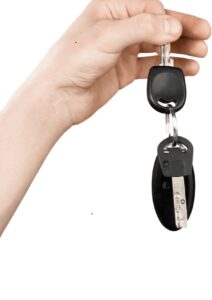 A hand holding a set of car keys with a black key fob, perfect for illustrating Car Key Replacement services.